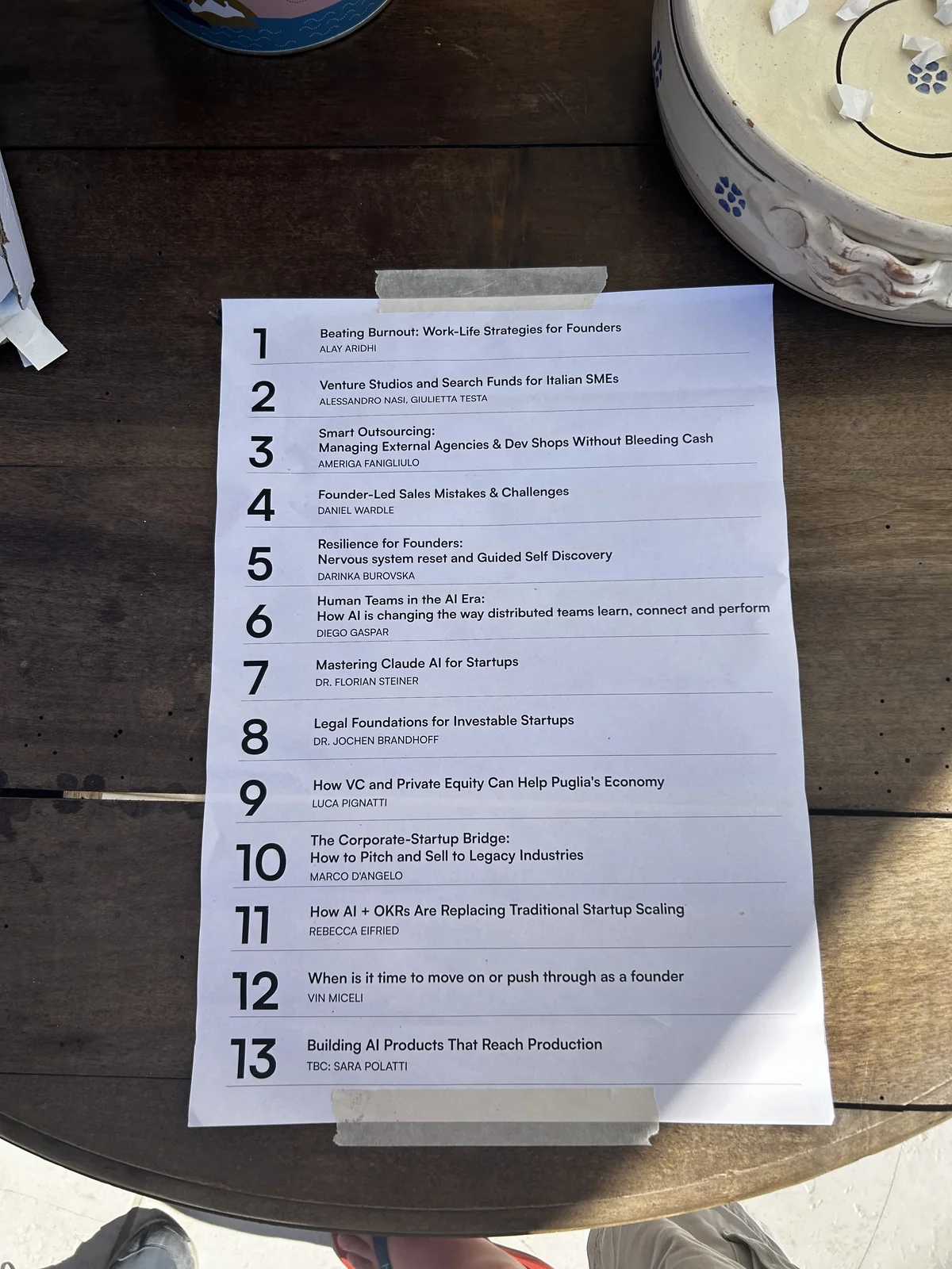 Das gedruckte Roundtable-Programm, mit Klebeband auf einem Holztisch am Strand befestigt